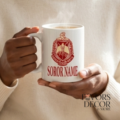 Person holding a mug with a sorority logo and text.